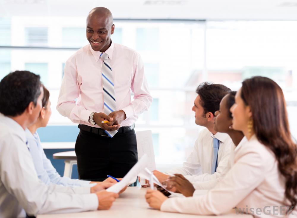 man-in-pink-shirt-standing-and-looking-at-five-seated-people